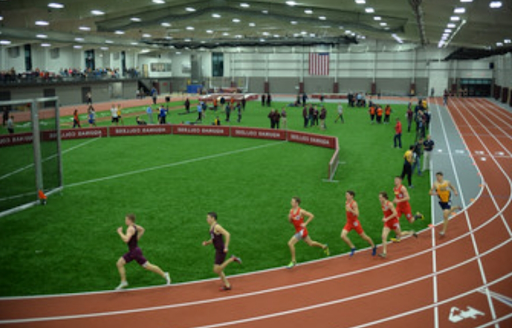 Alkinsis indoor track and field. Athletes run on the track in the foreground.