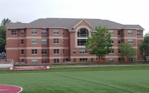 St. Rose of Lima Hall as viewed from the Soccer field. Red brick building with four stories and a large arched window in the center.